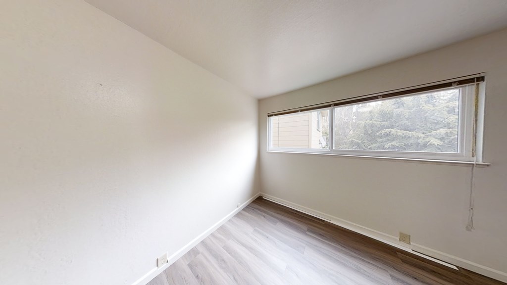 A room with a window and a white wall.