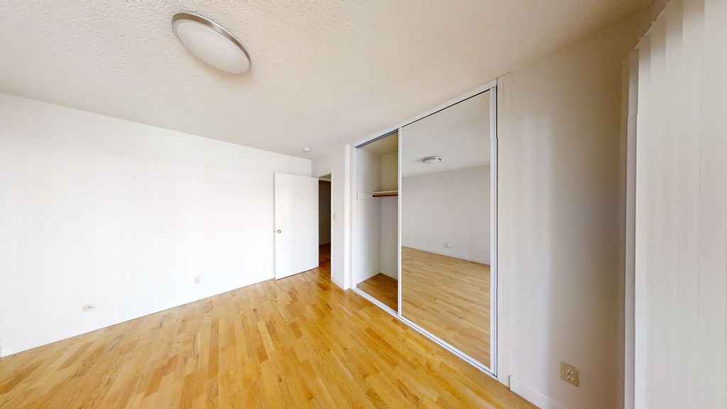 A room with a wooden floor and a mirror on the wall.