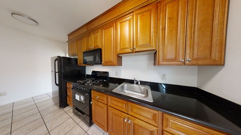 A kitchen with wooden cabinets and black countertops.