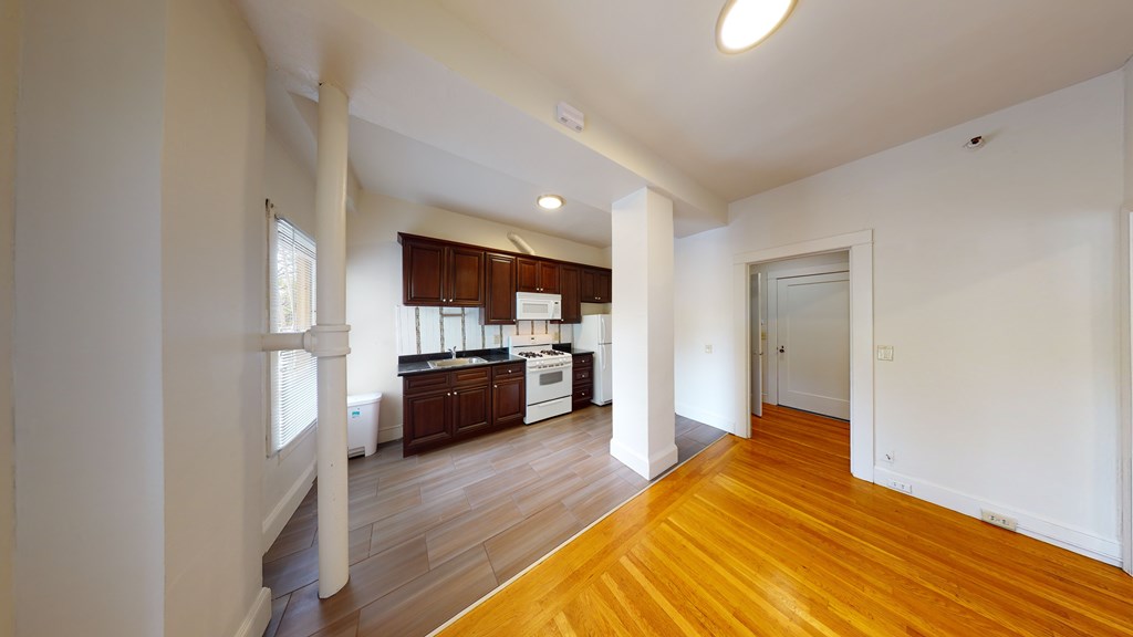 A spacious kitchen with wooden floors and white walls.