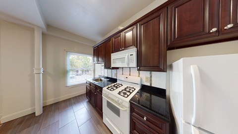 A kitchen with white appliances and dark wood cabinets.