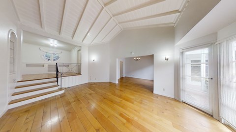 A spacious room with wooden floors and white walls.