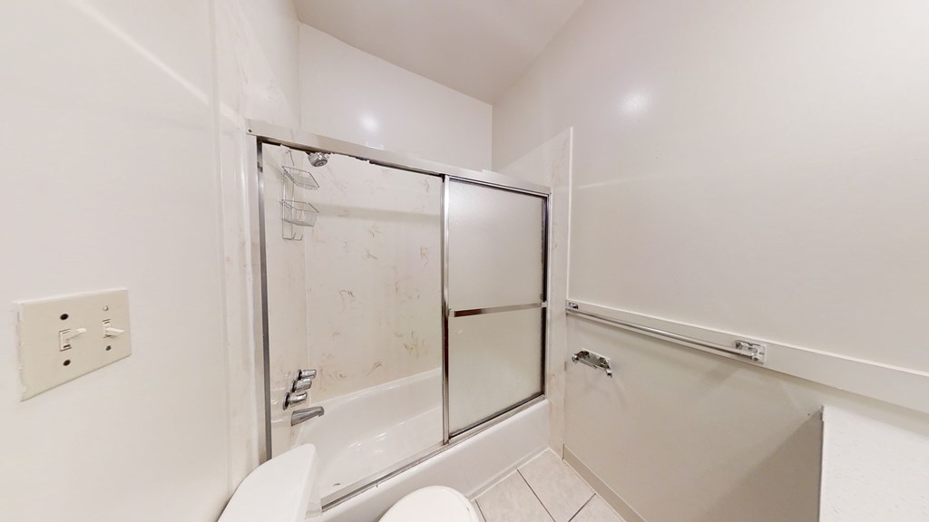 A white bathroom with a toilet, sink, and shower.