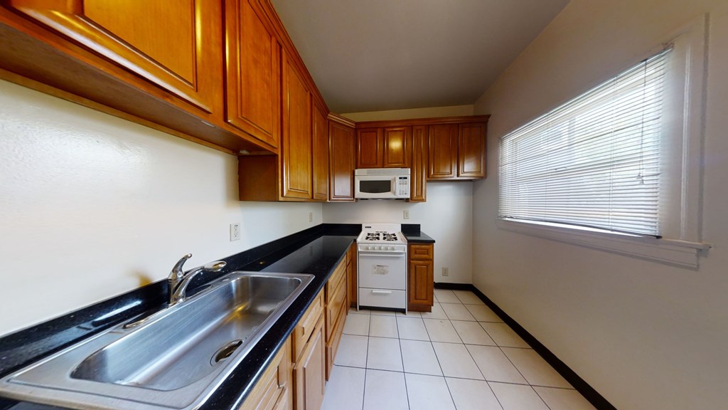A kitchen with wooden cabinets and a black countertop.