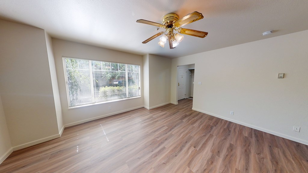 A room with a ceiling fan and wooden flooring.