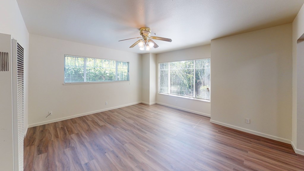 A room with a ceiling fan and wooden flooring.