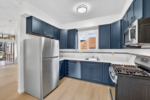 A kitchen with a stainless steel refrigerator and dark blue cabinets.