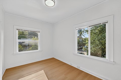 A room with a window showing a view of a street and trees.