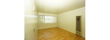 A room with wooden floors and a window with blinds.