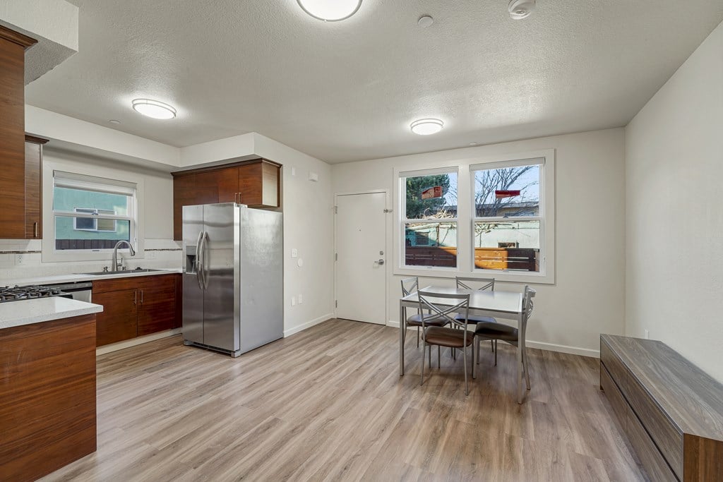 A kitchen with a refrigerator, stove, and table.