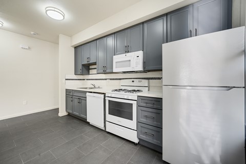 A modern kitchen with white appliances and grey cabinets.