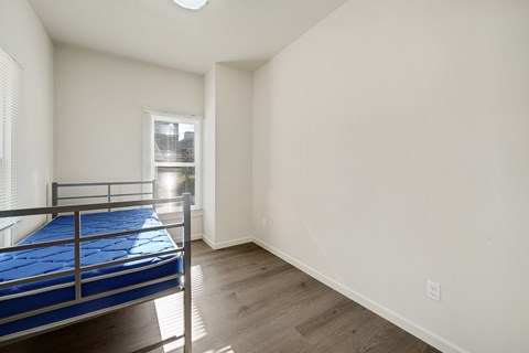 A bedroom with a blue mattress and wooden flooring.