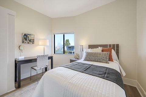 A bedroom with a large bed and a desk with a chair.