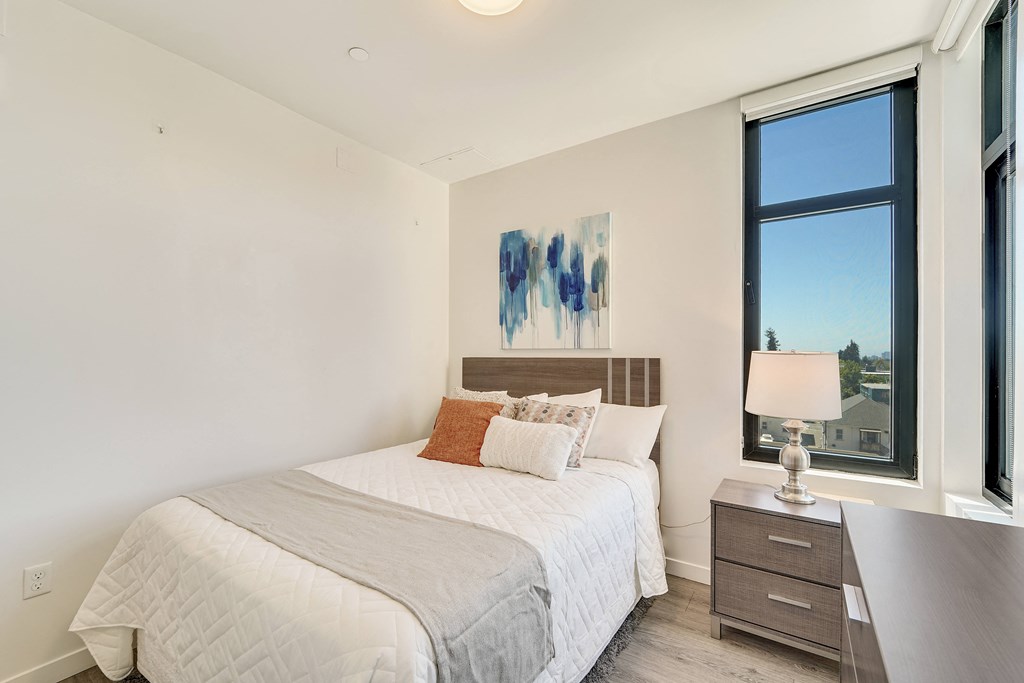 A bedroom with a large bed and a painting on the wall.