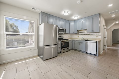 A kitchen with a refrigerator, oven, and microwave.