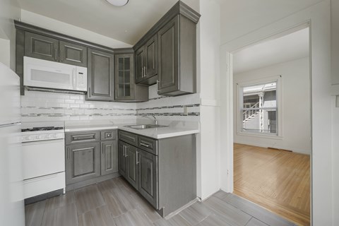 A kitchen with white appliances and dark wood cabinets.