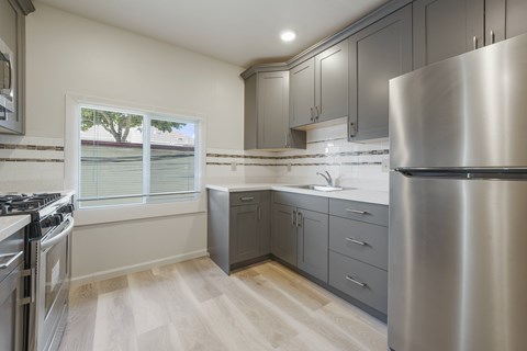A modern kitchen with a stainless steel refrigerator and wooden flooring.