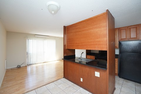 A kitchen with wooden cabinets and a black fridge.