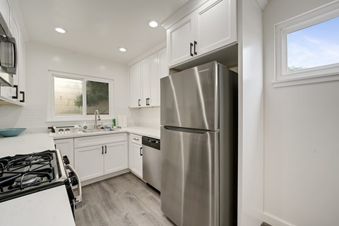 A modern kitchen with a stainless steel refrigerator and a black gas stove.