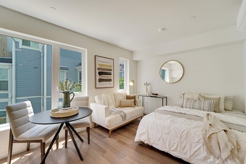 A bedroom with a white bed and a round mirror on the wall.