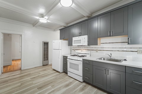 A kitchen with white appliances and grey cabinets.