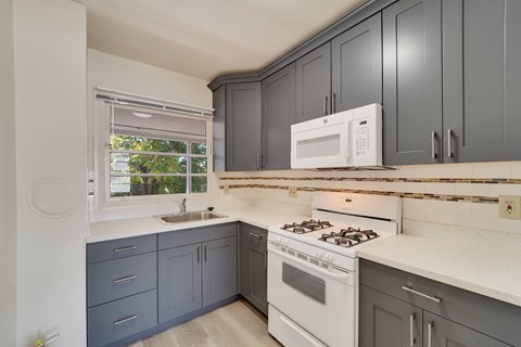 A kitchen with a white stove and a white microwave.