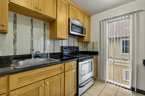 A kitchen with wooden cabinets and a black countertop.