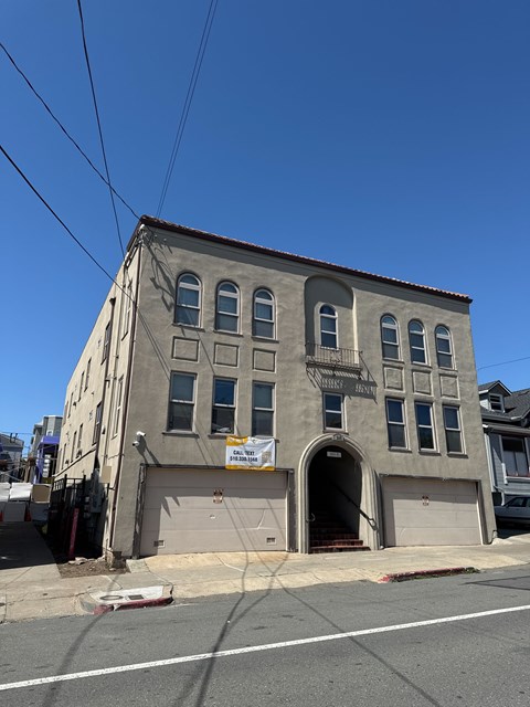 A building with a sign that says "FOR RENT" is located on the corner of a street.