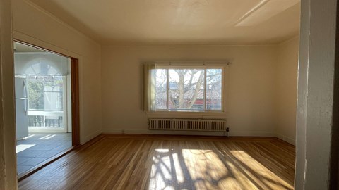 the living room of a house with wood floors and a window