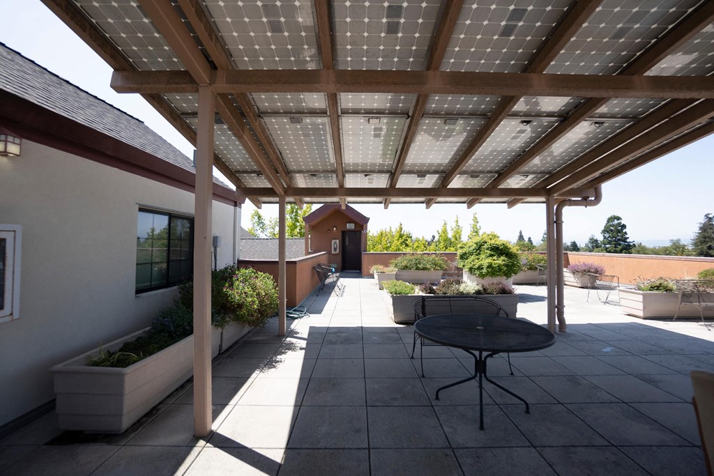A patio with a table and chairs under a roof with solar panels.