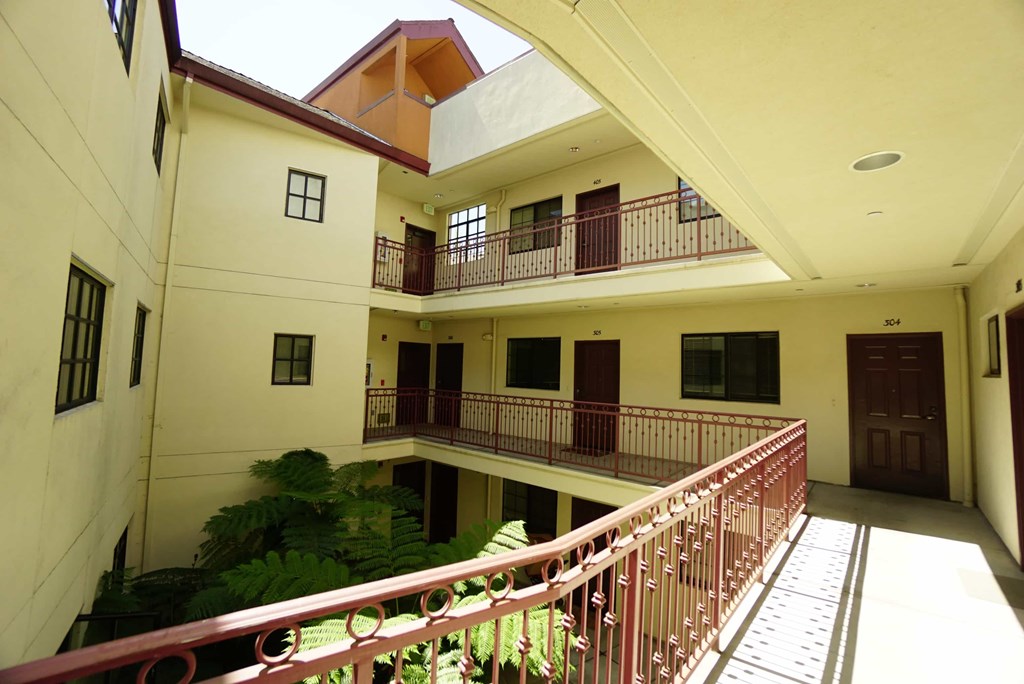 A balcony with a red railing is in the foreground of a building.