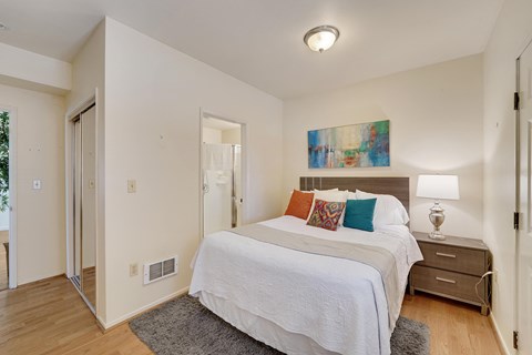 A bedroom with a white bed and a painting on the wall.
