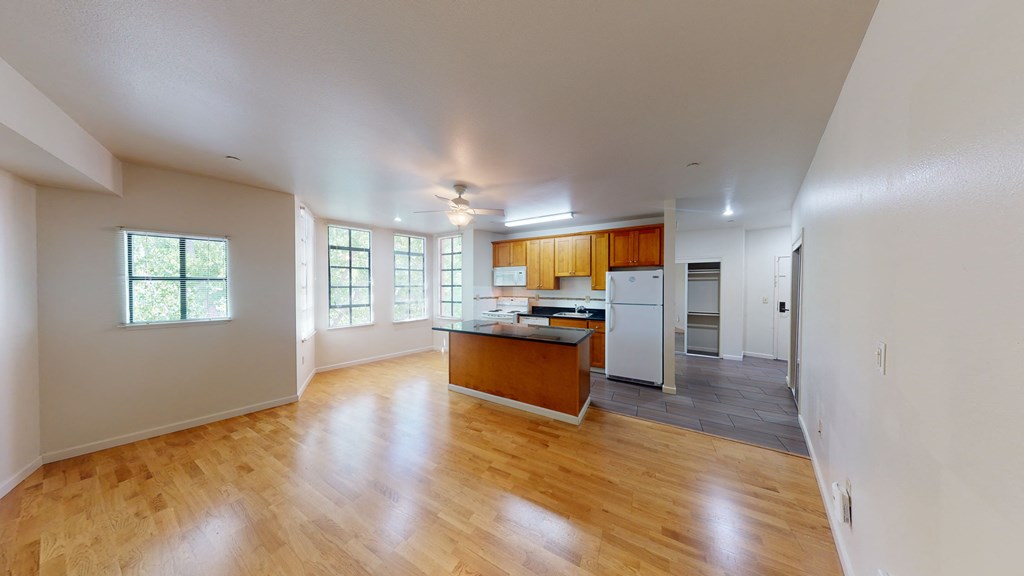 A spacious room with wooden floors and a kitchen area.
