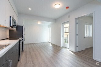 a kitchen and living room with white walls and wood floors