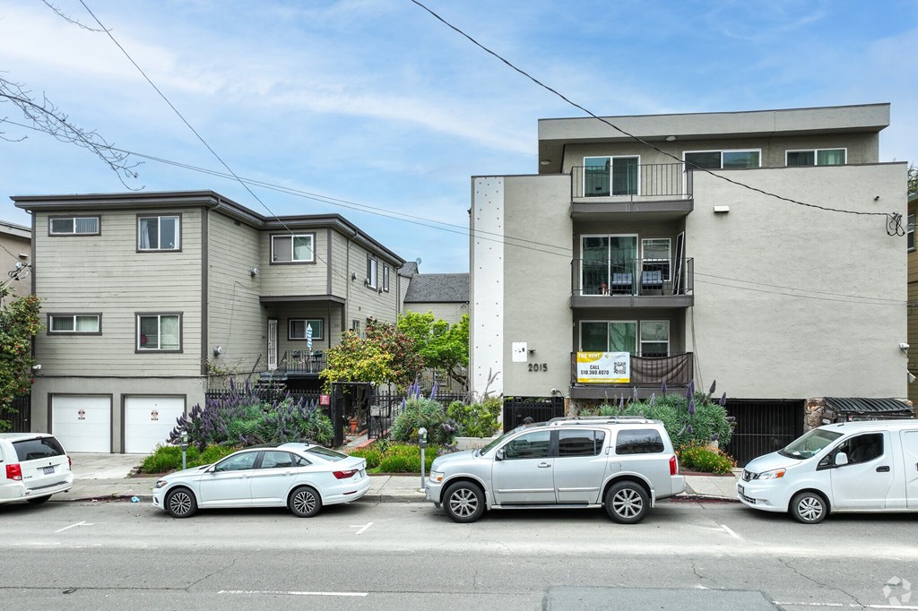 A row of houses with cars parked in front.