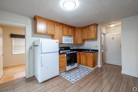 A kitchen with wooden cabinets and a white fridge.