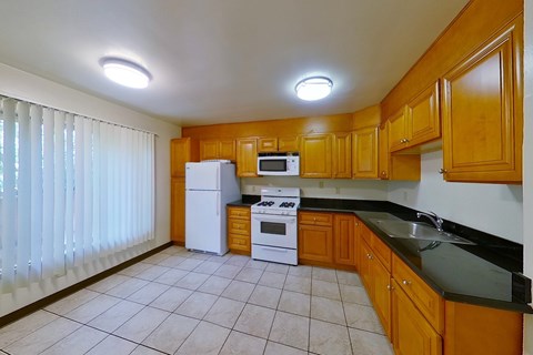 A kitchen with wooden cabinets and black countertops.