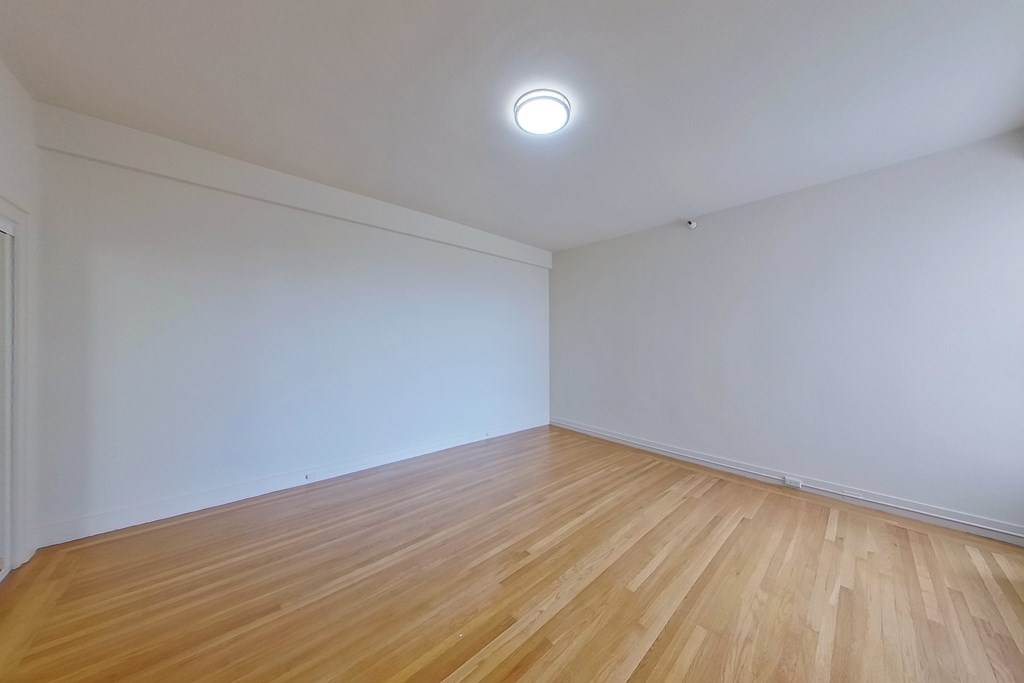 A room with wooden flooring and a ceiling light.