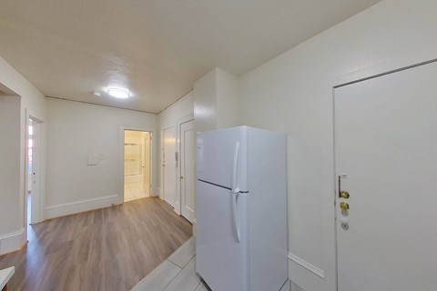 A white refrigerator in a kitchen with wood flooring.