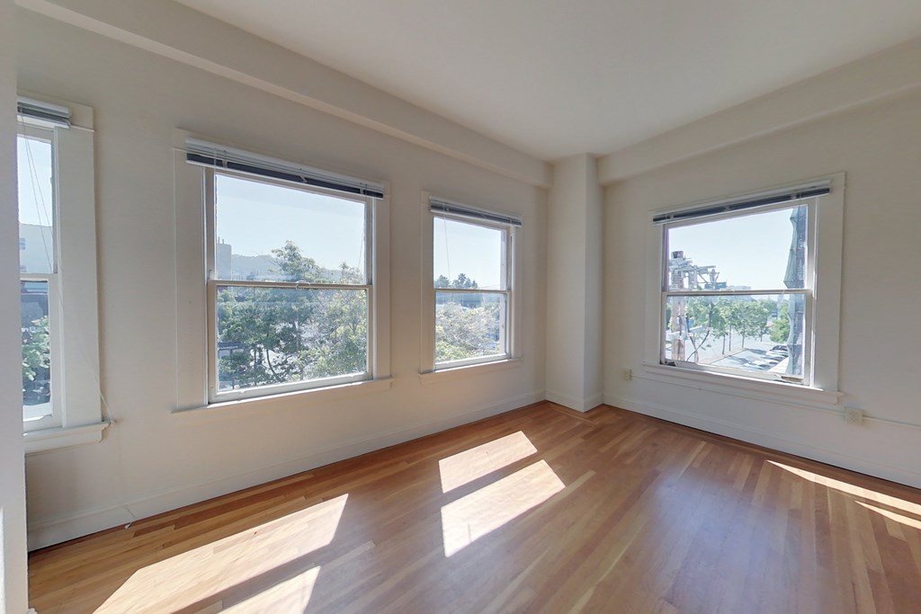 Three windows in a white room with wooden floors.