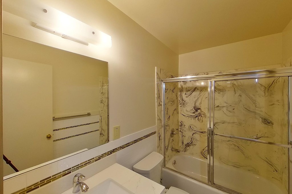 A bathroom with a marble shower and a white sink.