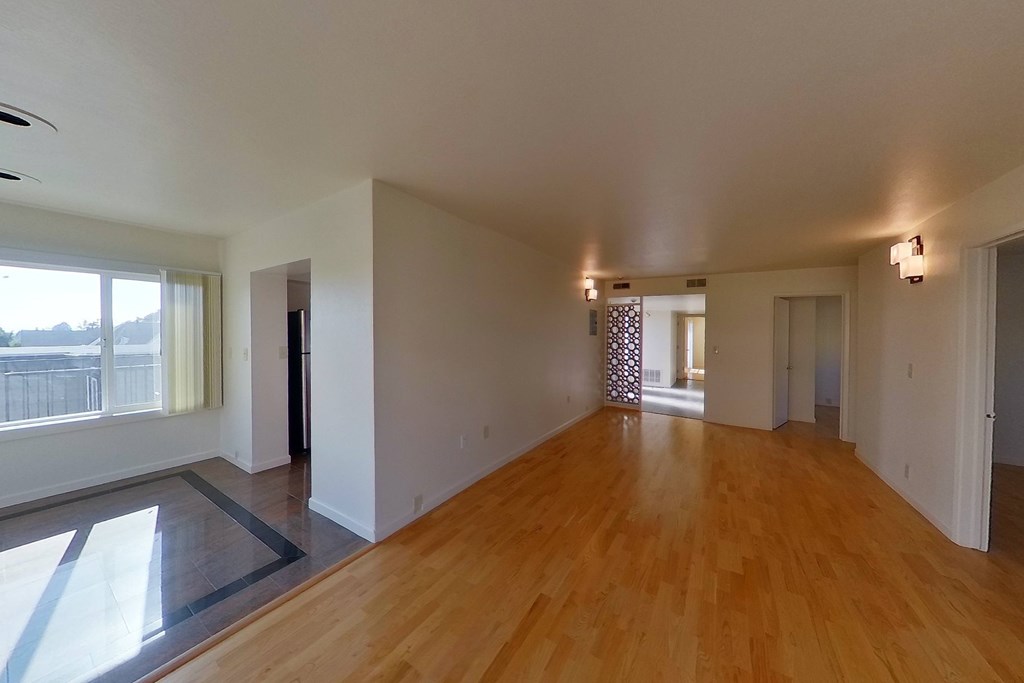 A spacious room with wooden floors and white walls.