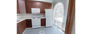 an empty kitchen with white appliances and wooden cabinets