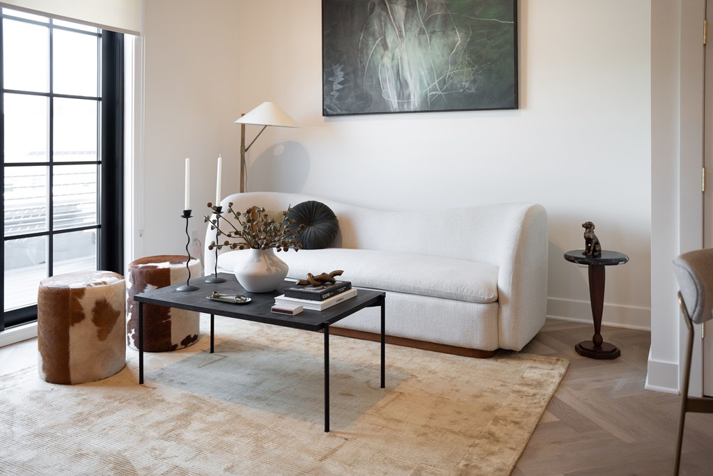 A living room with a white couch, a coffee table, and a painting on the wall.