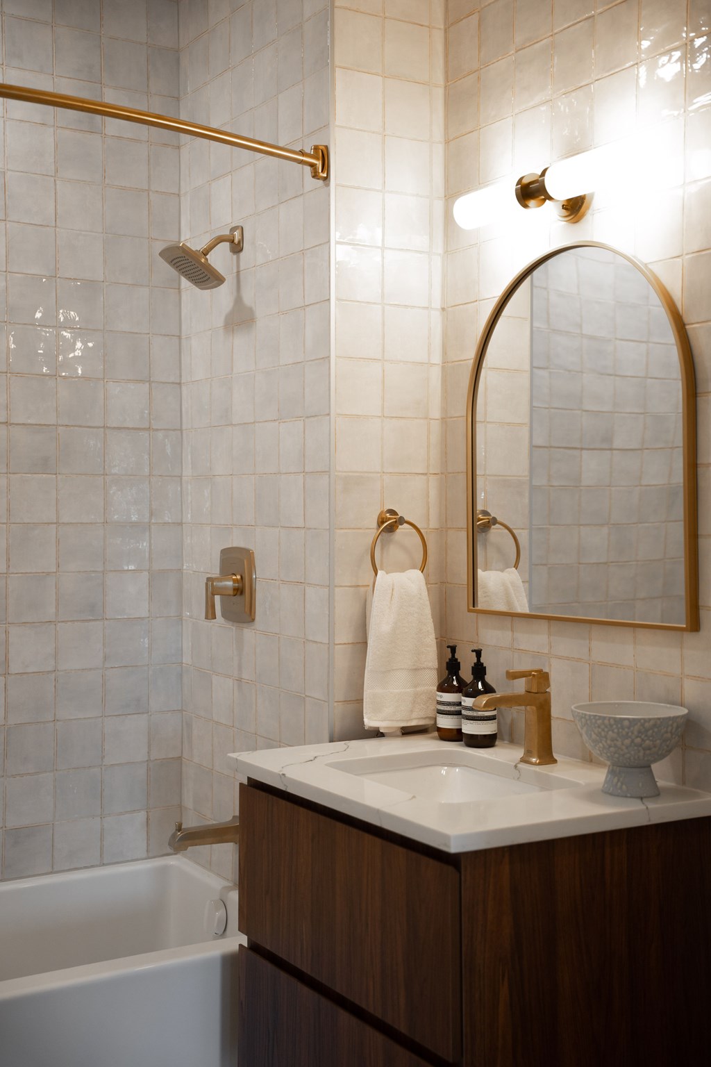 A white sink with a gold faucet and a gold mirror above it.