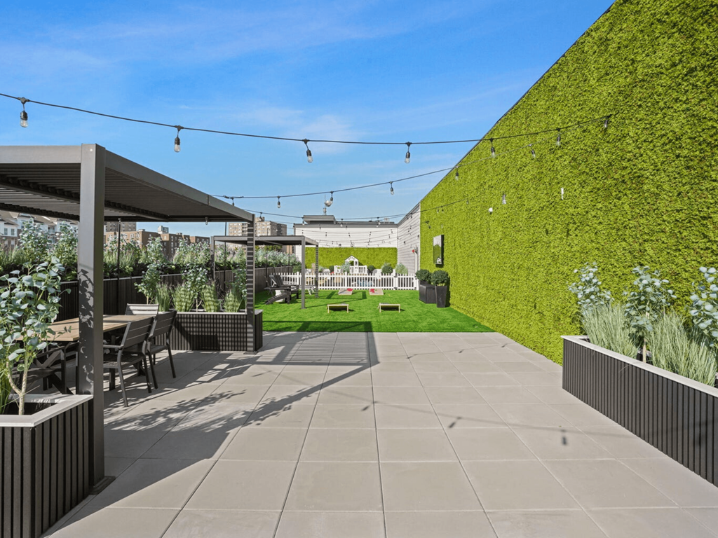 a courtyard with a green wall and a patio with tables and chairs