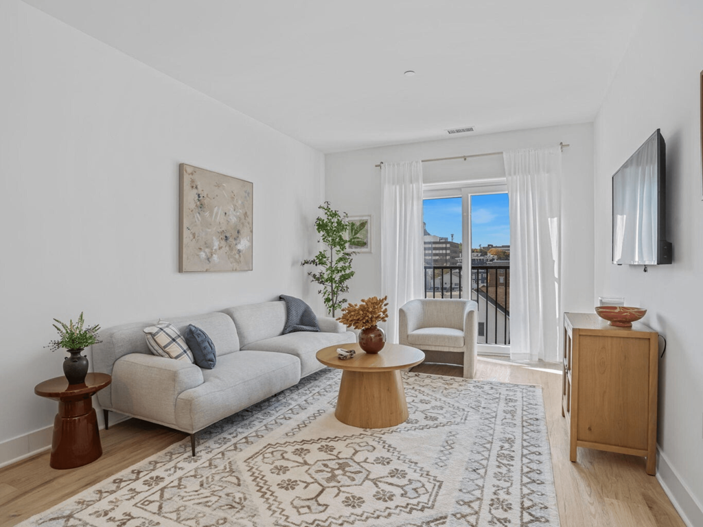 a living room with a couch and a rug and a door to a balcony