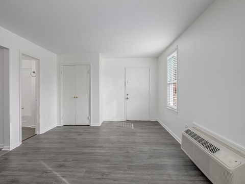 A room with a grey floor and white walls with a window and a radiator.
