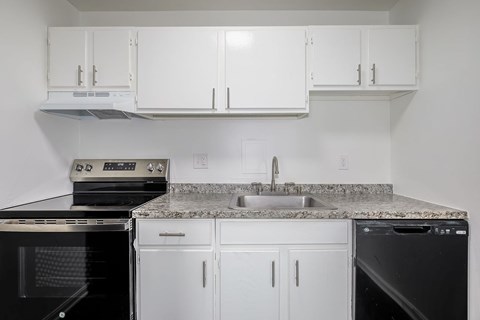A kitchen with white cabinets and black appliances.