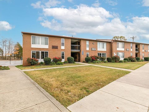 A row of red brick apartment buildings with green lawns in front.